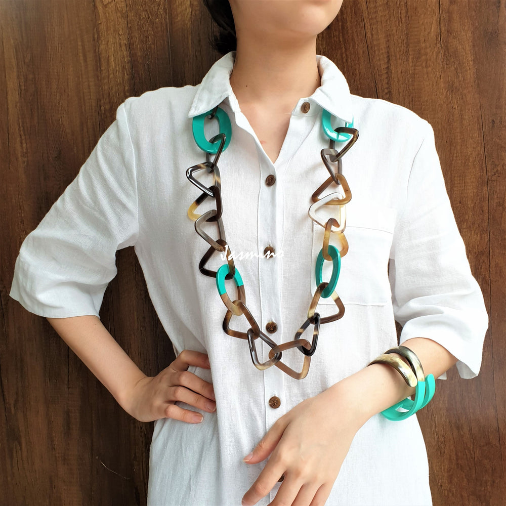 
                  
                    A model is wearing unique handmade necklace has several turquoise lacquered elliptical pieces on a light background, a unique gift for your friend
                  
                