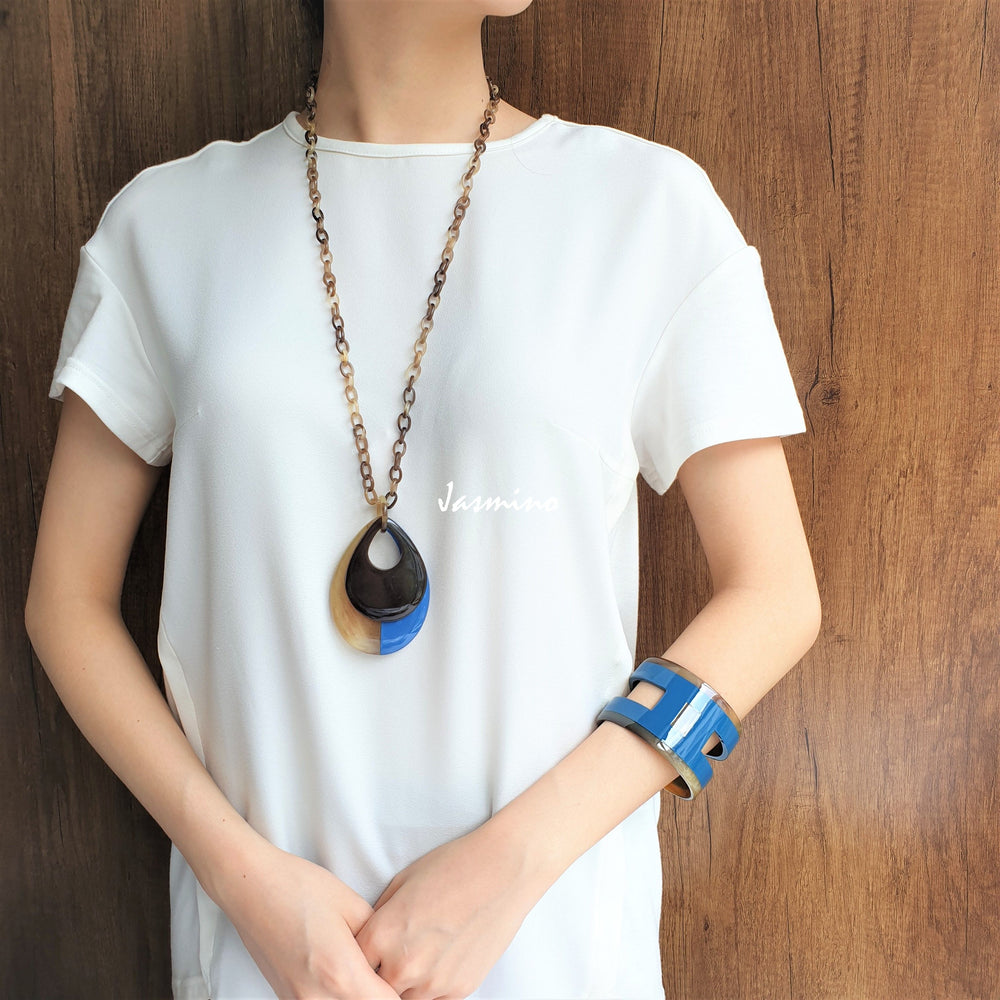 
                  
                    A women is wearing handmade Vintage double teardrop pendant features a black and sky blue colour made of natural buffalo horn
                  
                