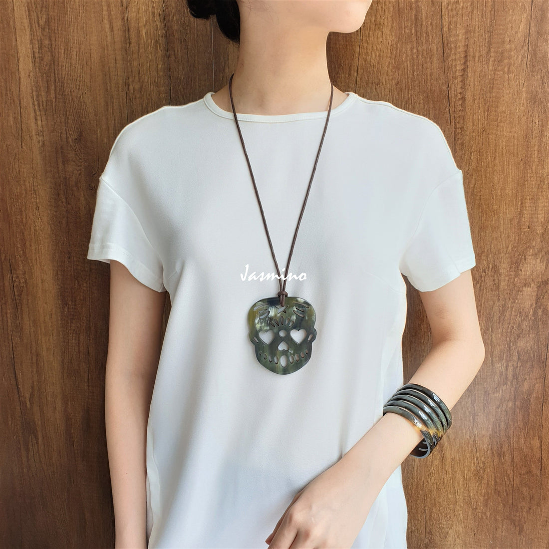 A model is wearing unique skull pendant feature greyish green made of natural buffalo horn for women and men and Halloween