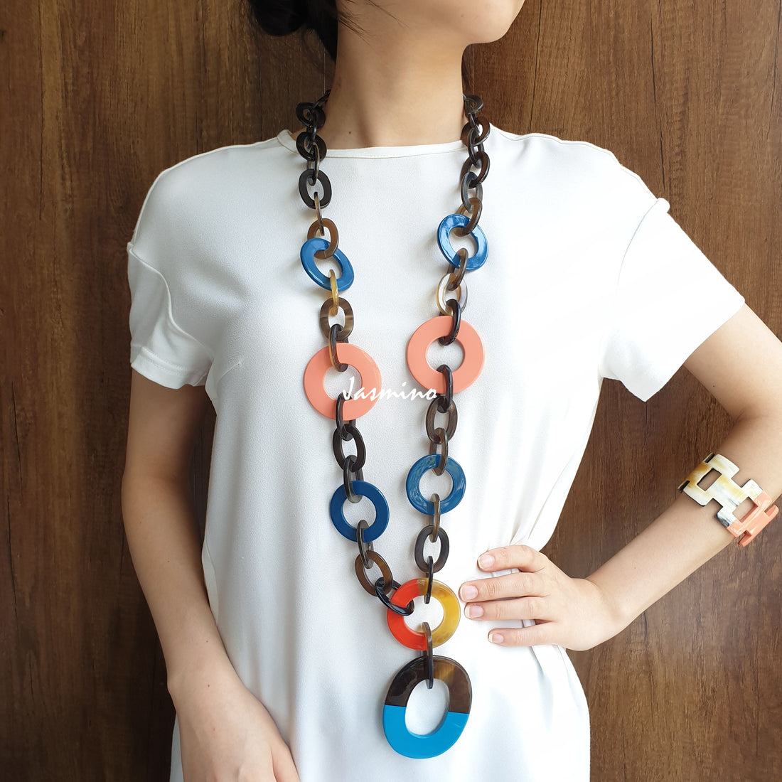 A model is wearing Jasmino unique handmade wide chain necklace featured blue, coral, brown, and coral in natural buffalo horn for women