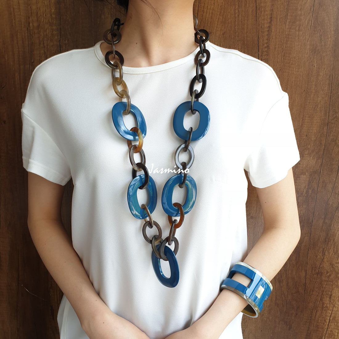 A model is wearing Jasmino unique handmade Vintage wide chain necklace and H-shaped cuff bracelet featured blue in natural buffalo horn for women