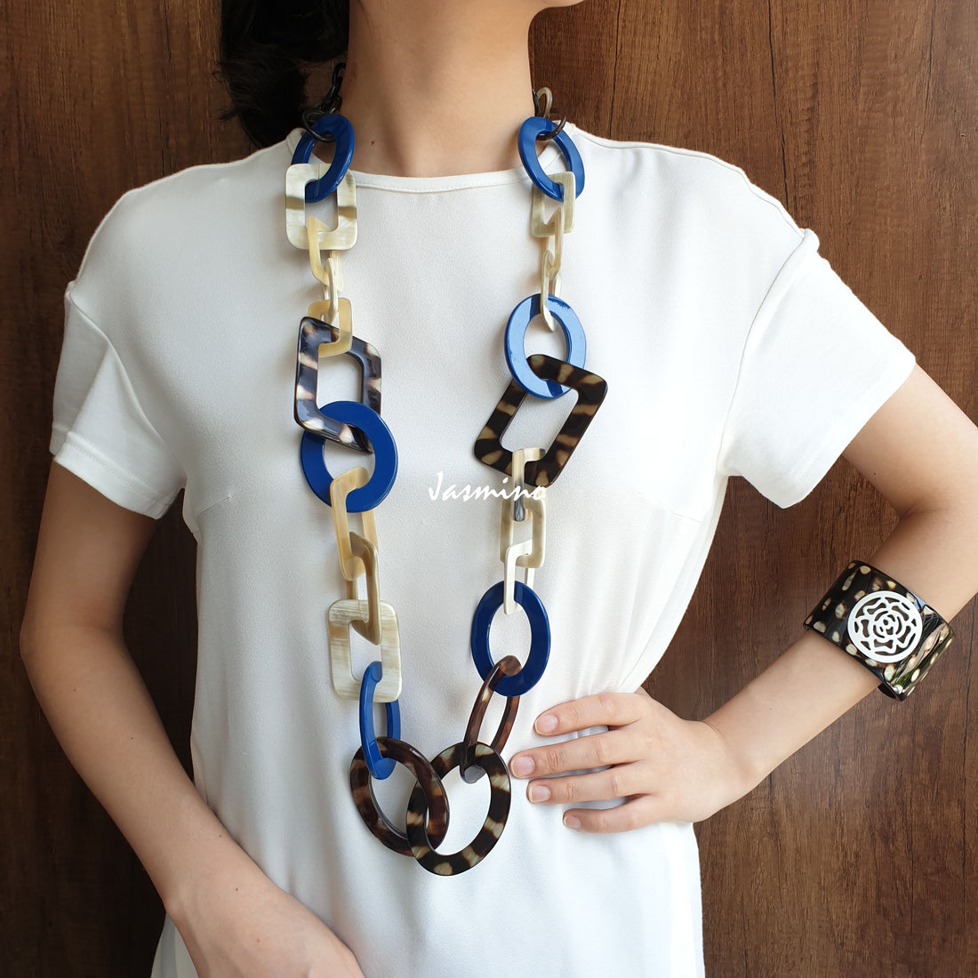 A model is wearing Jasmino unique handmade Bohemian and Vintage necklace detailed by an blue and spotted brown oval and rectangle in natural buffalo horn for women