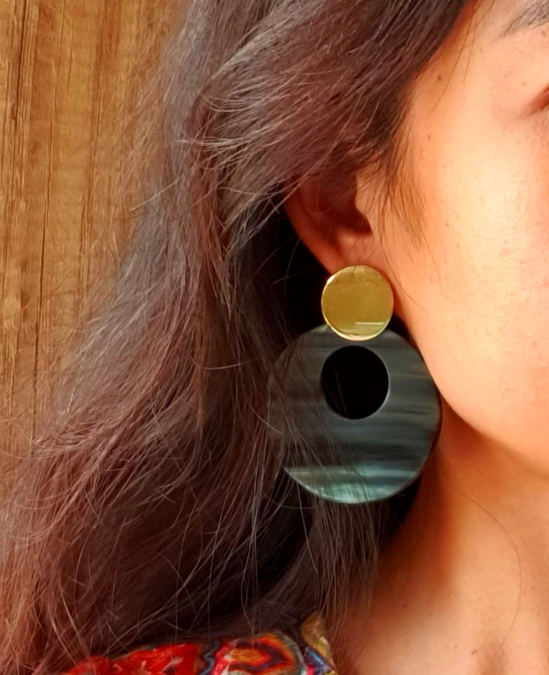 
                  
                    A woman is wearing grey full-moon circle drop earrings that are made by natural buffalo horn material 
                  
                