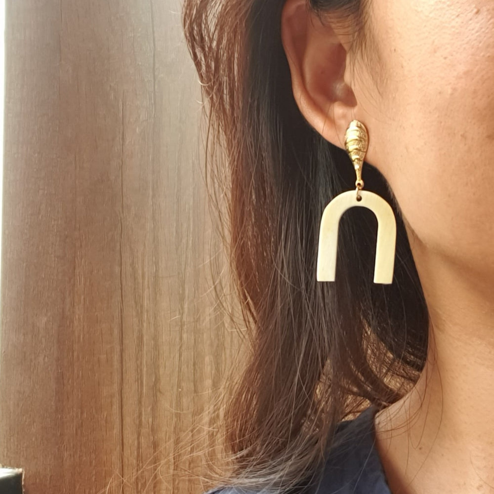 
                  
                    A woman wears a luxury U-shape drop earrings on a light background
                  
                