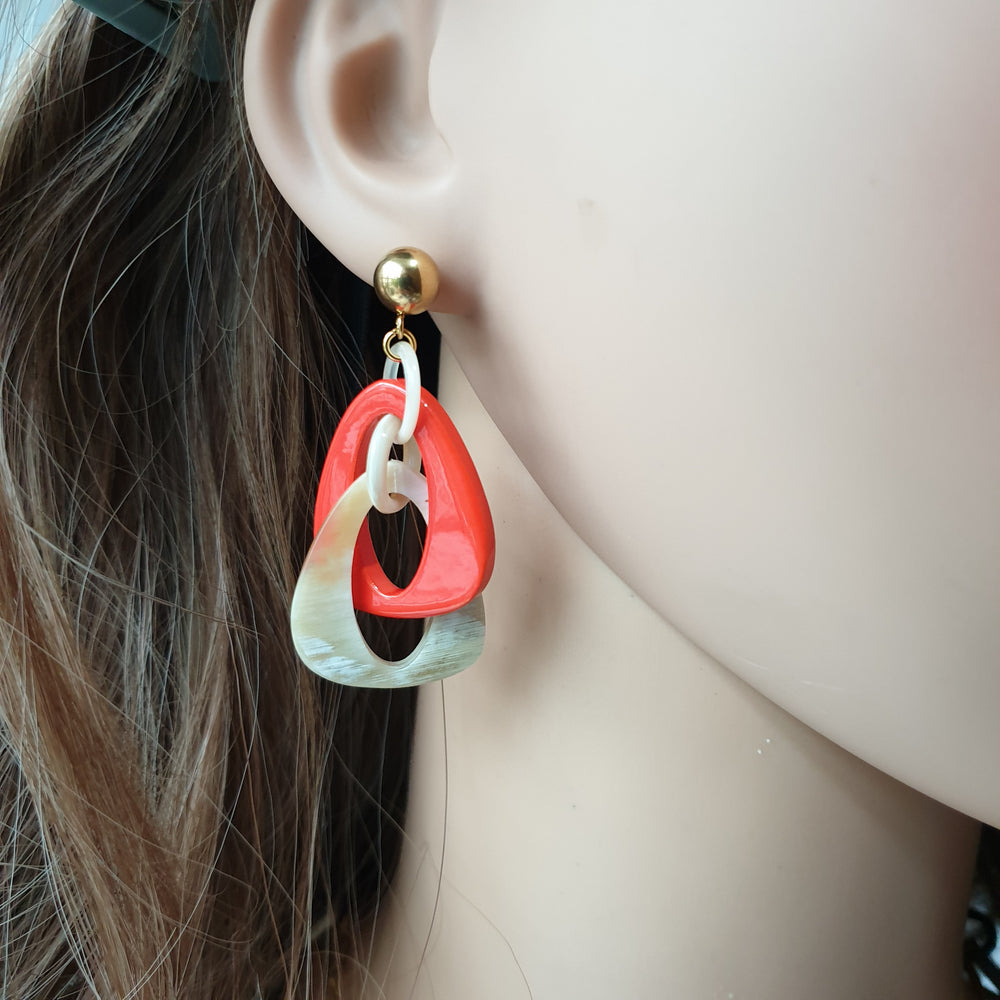
                  
                    handmade double triangle earrings feature white and orange red in natural buffalo horn for Spring 2023 on a mannequin
                  
                