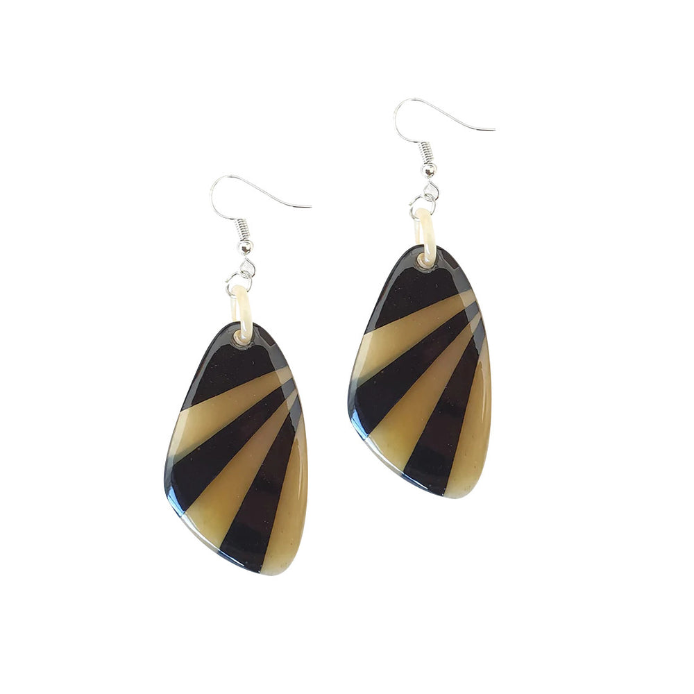 
                  
                    Handmade dangle earrings are shaped by seashells that feature amber and black color in the natural light
                  
                