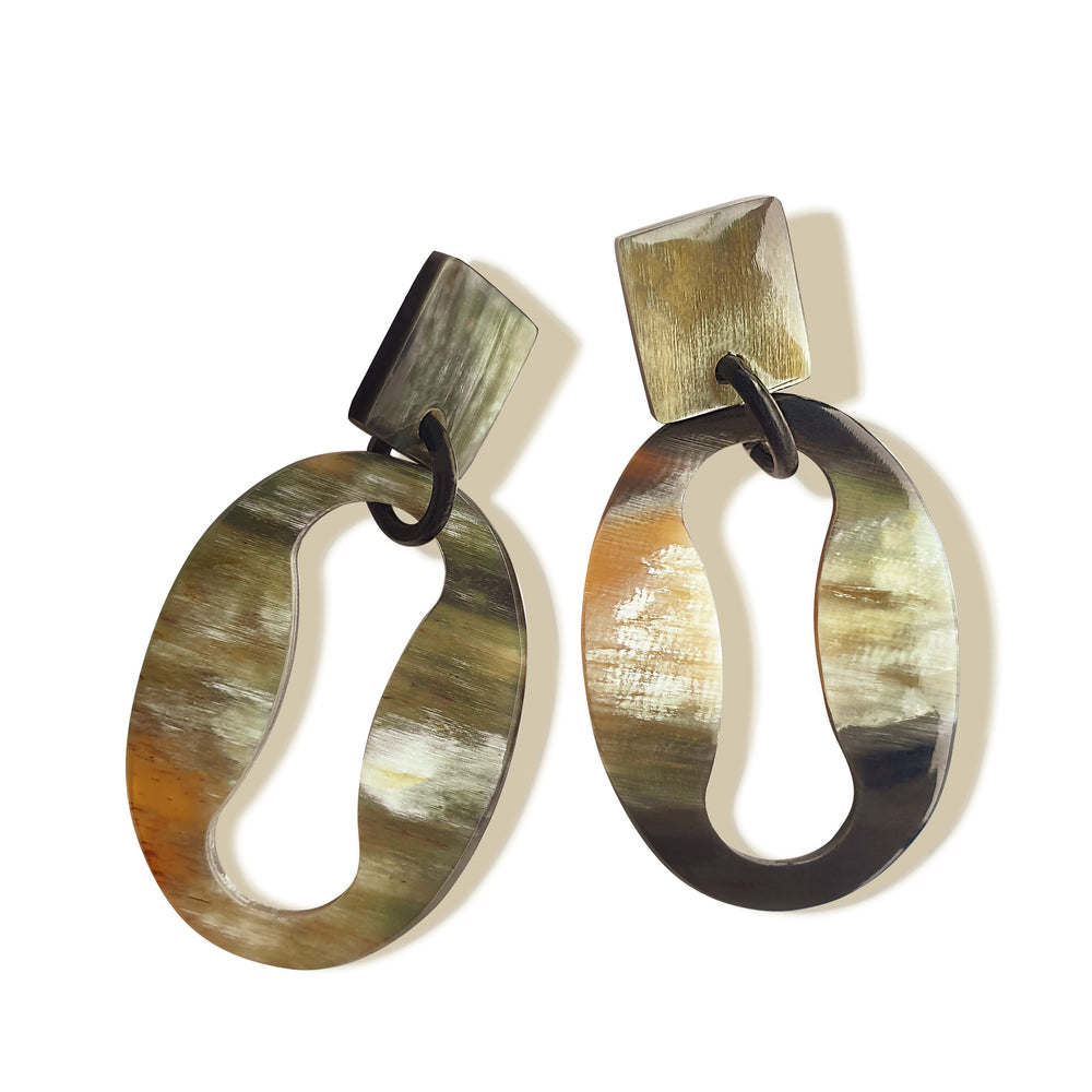 Handmade drop earrings are shaped by a mix of an oval and an infinity symbol featured light colors in the natural light