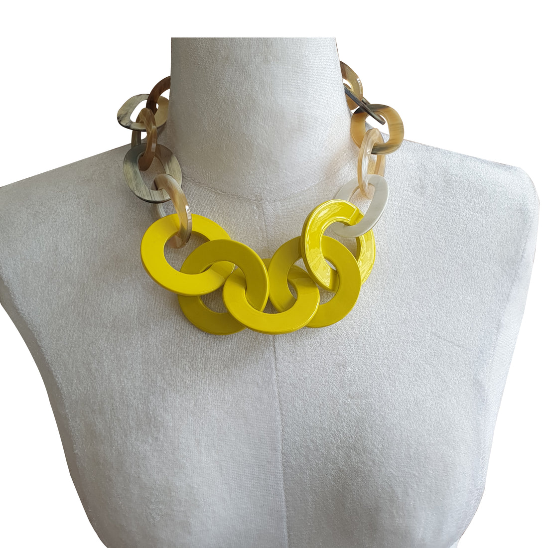 A wide chain necklace has central 5 yellow pendants that are worn by a mannequin in the natural light
