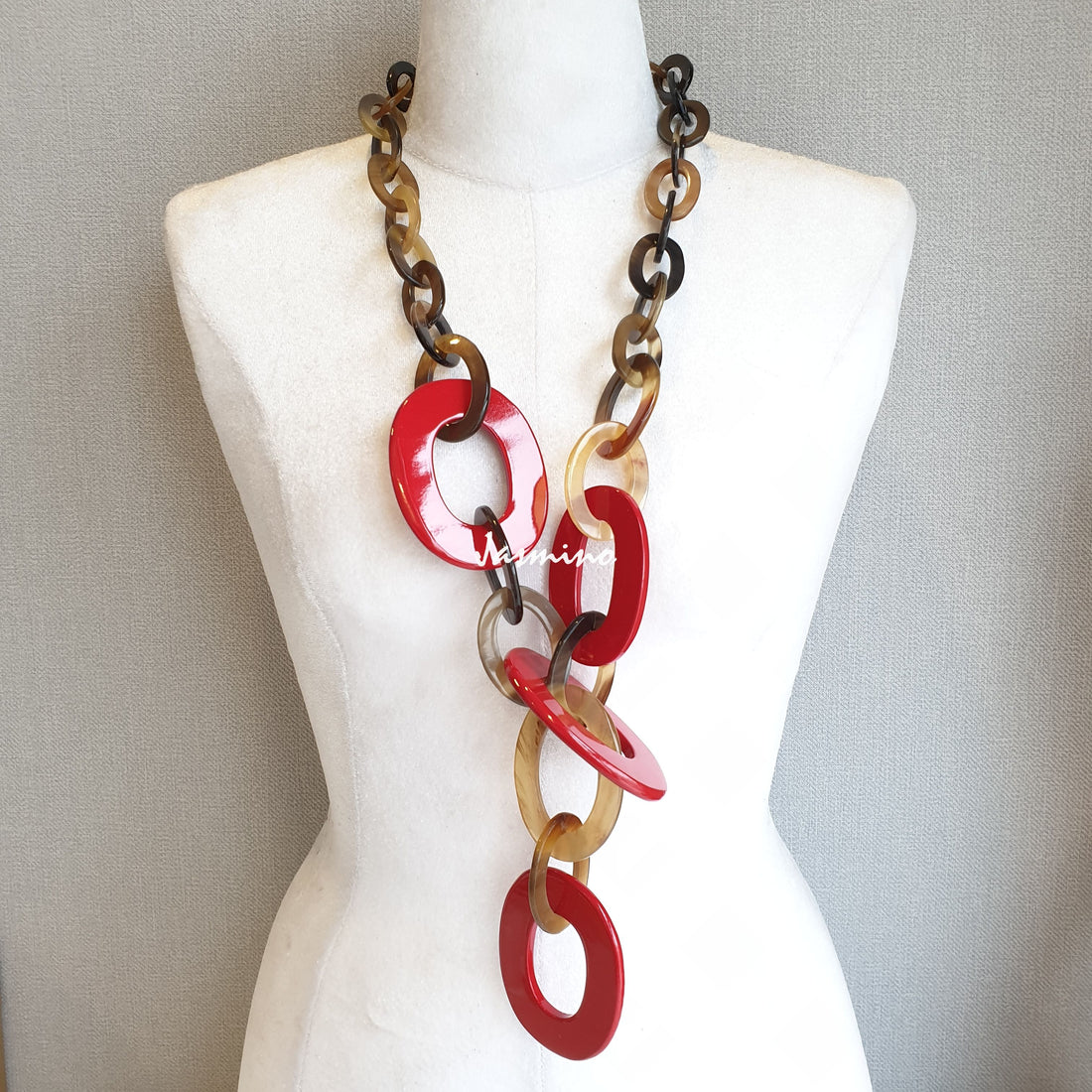 A red wide chain necklace features natural buffalo horn worn by a mannequin