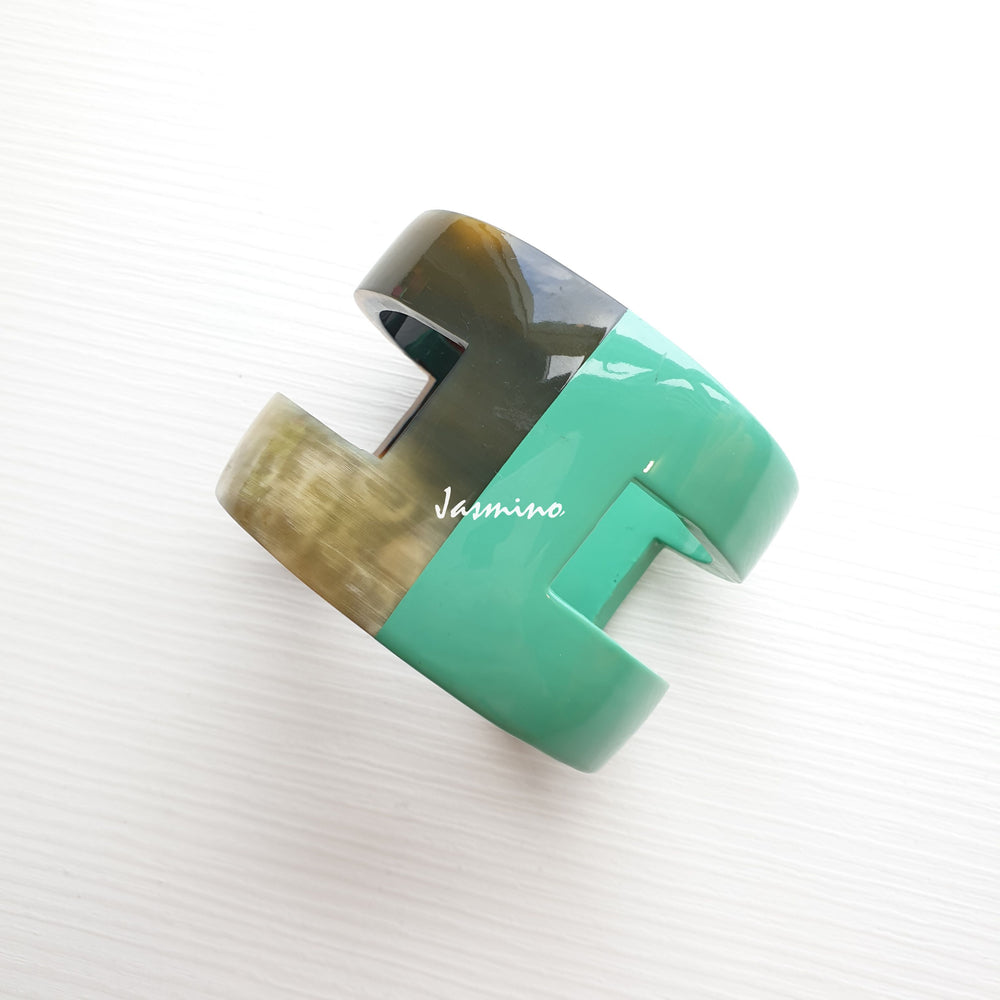 
                  
                    A cuff bracelet is designed by a turquoise and brown color and made by natural buffalo horn
                  
                