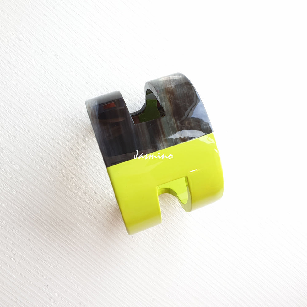 
                  
                    the cuff  bracelet is designed with half natural buffalo horn and half lime  green lacquer on the light background
                  
                
