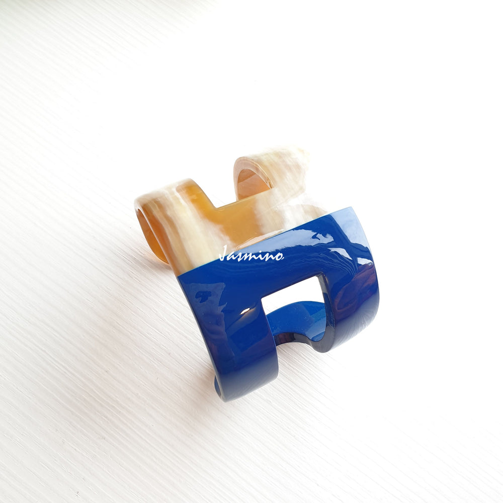 
                  
                    A cuff bracelet is designed with half natural buffalo horn and half navy blue lacquer in natural light 
                  
                
