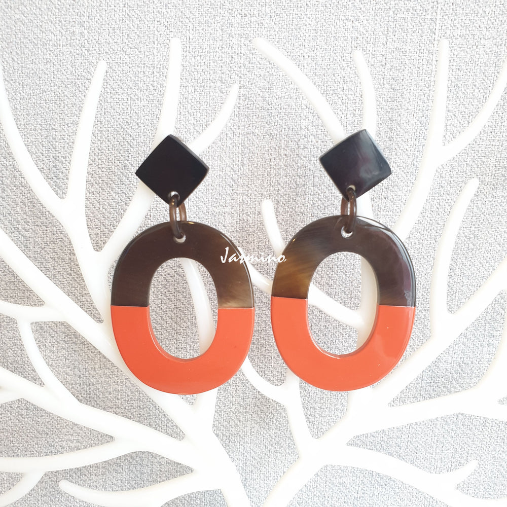 
                  
                    Handmade oval earrings are covered by a brown and orange color for a unique gift on a white background
                  
                