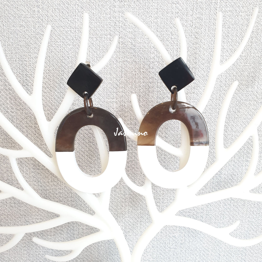 
                  
                    Handmade oval earrings are covered by a brown and white color for a unique gift on white faux branches
                  
                