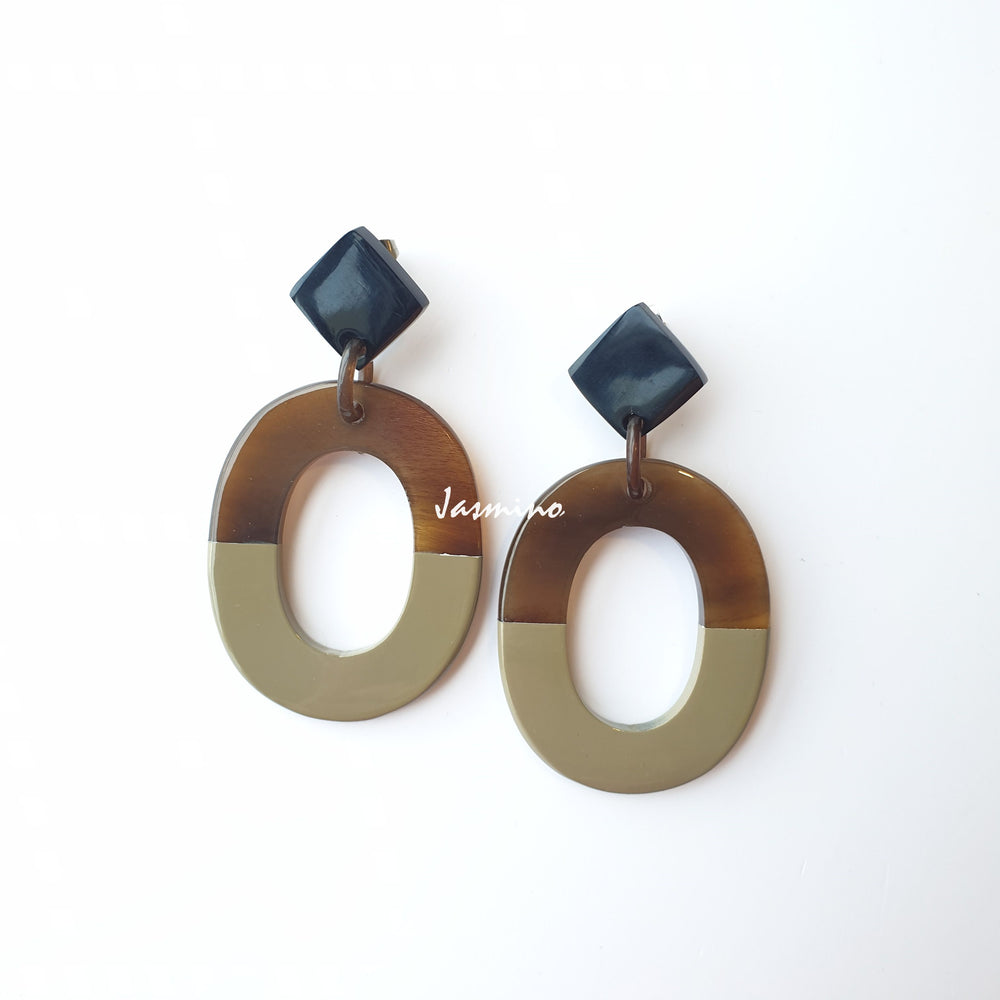 
                  
                    Handmade oval earrings are covered by a brown and beige color for a unique gift on a white background
                  
                
