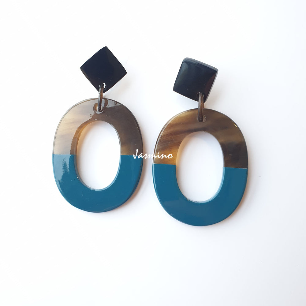 
                  
                    Handmade oval earrings are covered by a brown and blue color for a unique gift on a white background
                  
                