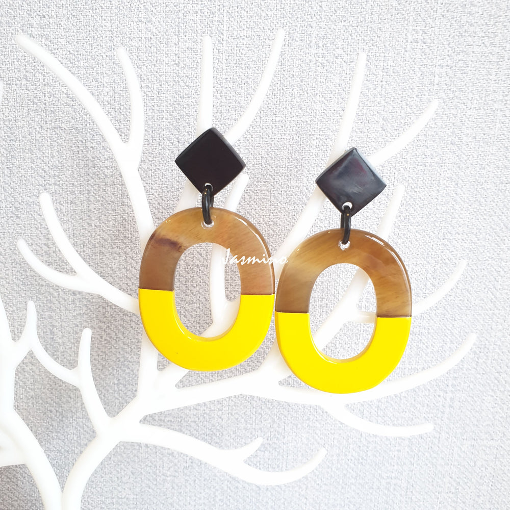 
                  
                    Handmade oval earrings are covered by a brown and yellow color for a unique gift on a white background
                  
                