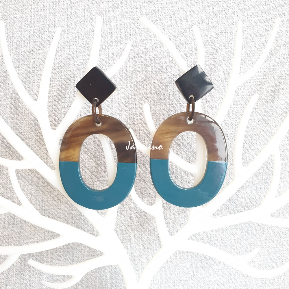 
                  
                    Handmade oval earrings are covered by a brown and navy blue color for a unique gift on white faux branches
                  
                