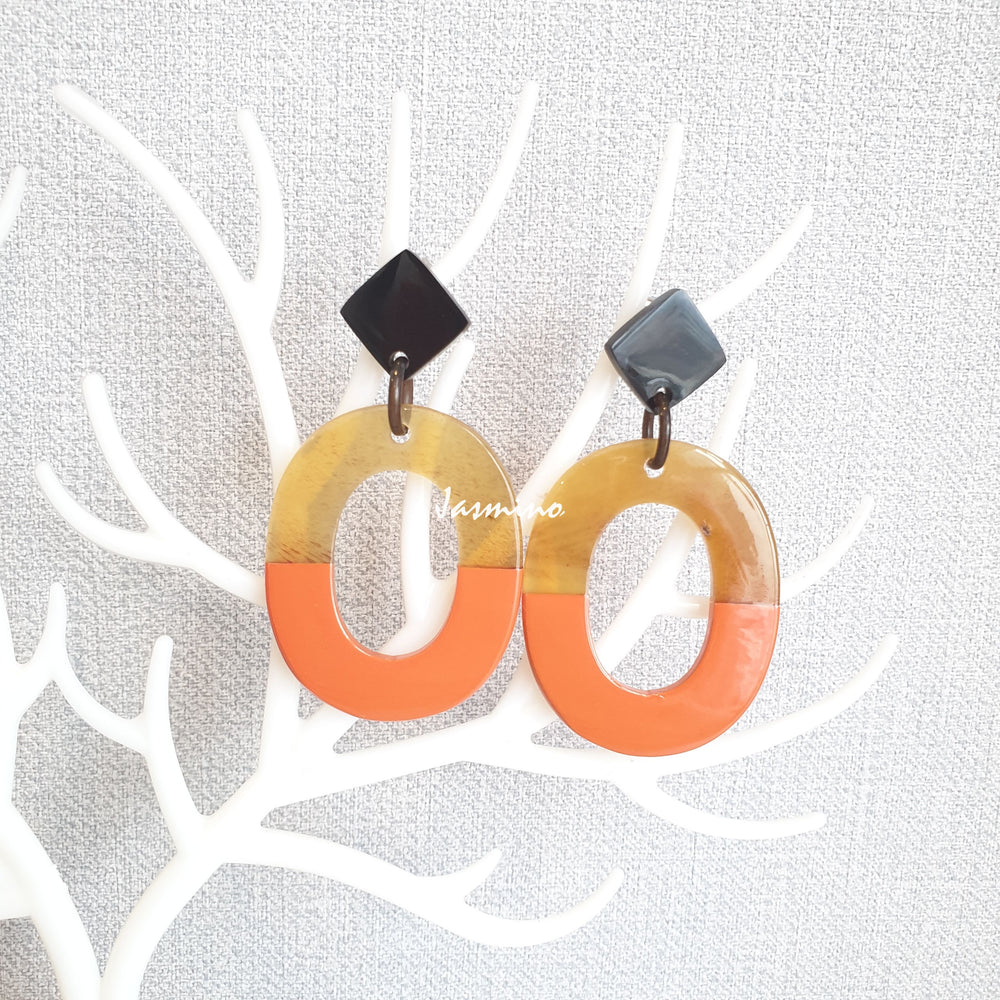 
                  
                    Handmade oval earrings are covered by a brown and orange color for a unique gift on a white background
                  
                