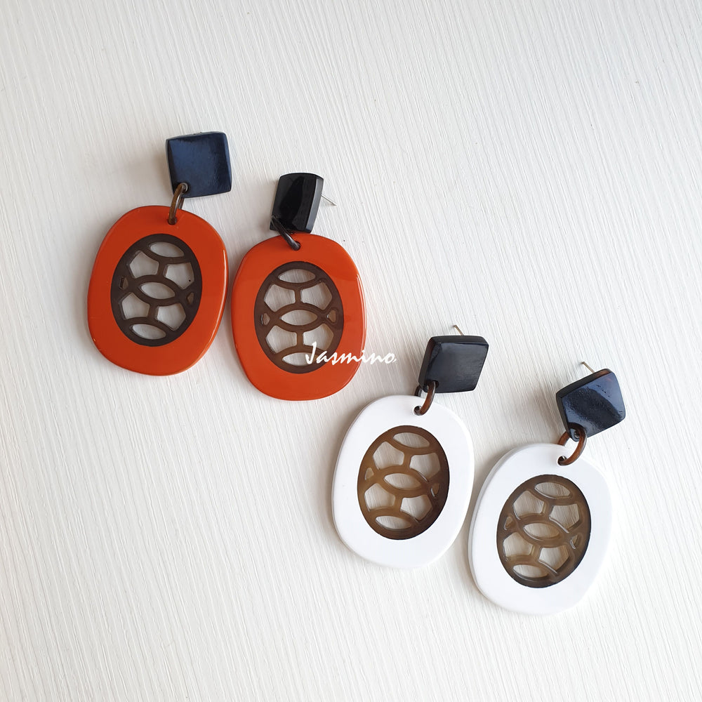 
                  
                    A set of two pairs of oval drop earrings feature orange and white color made of natural buffalo horn
                  
                