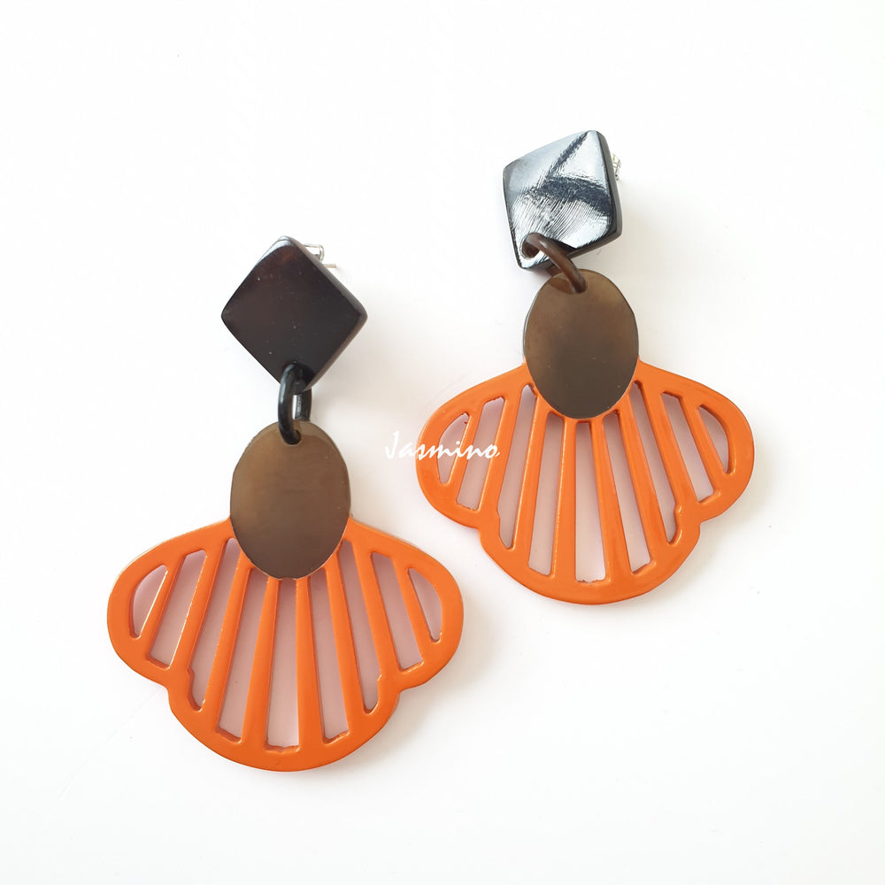 
                  
                    Handmade drop earrings are shaped by seashells with an orange color in the natural light
                  
                