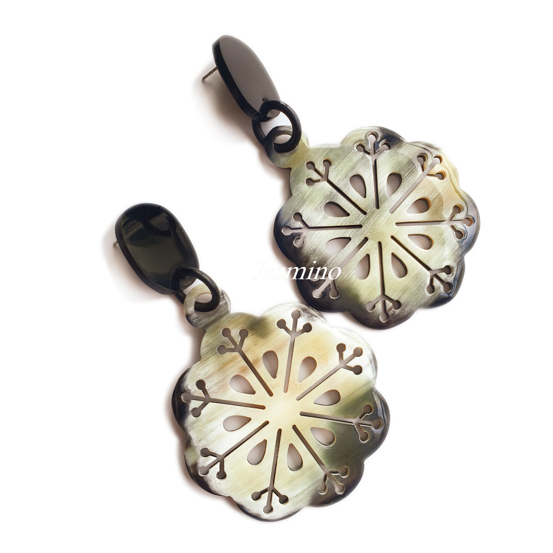 Handmade drop earrings are shaped by snowflakes with white and brown color in the natural light