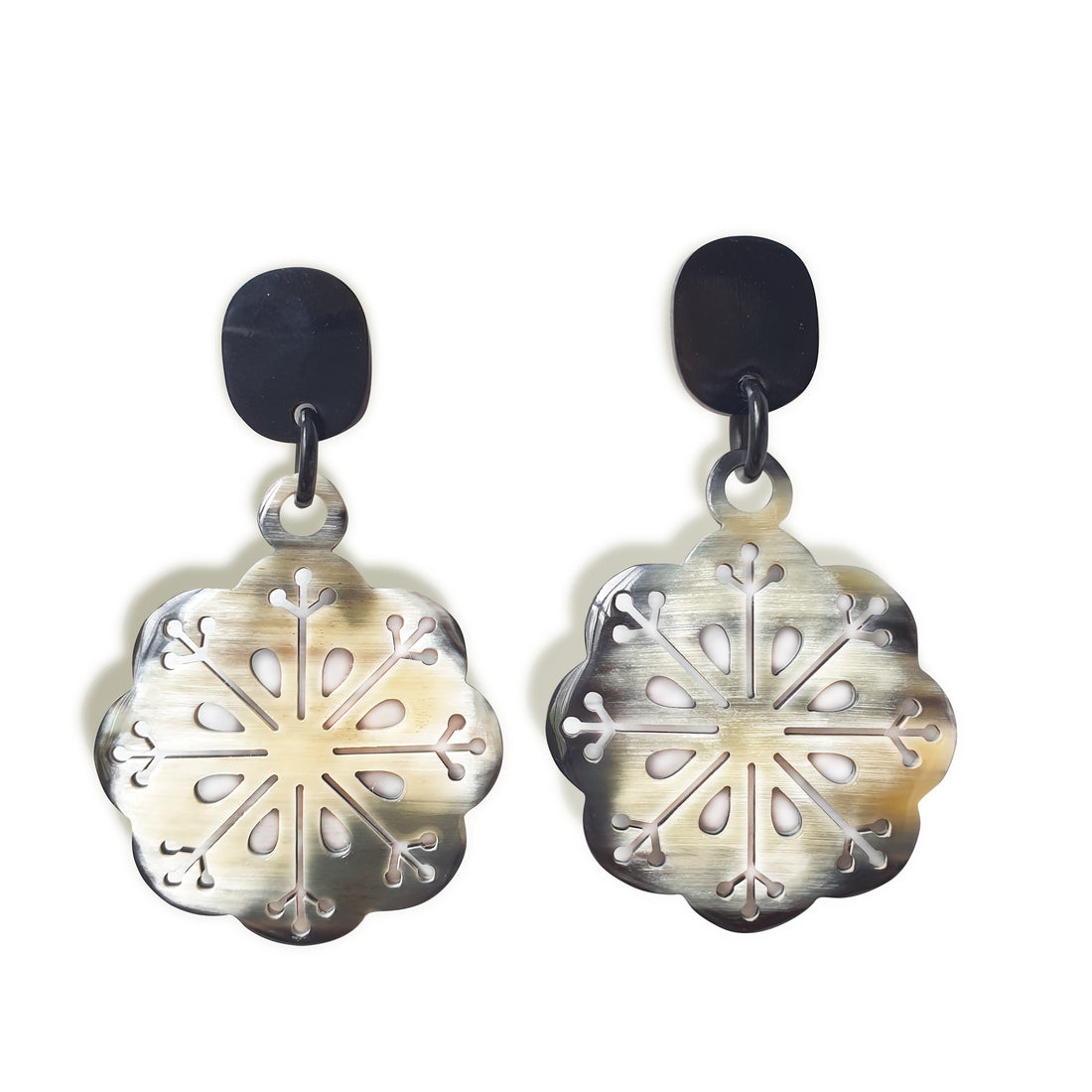 Handmade drop earrings are shaped by snowflakes with white and brown color in the natural light