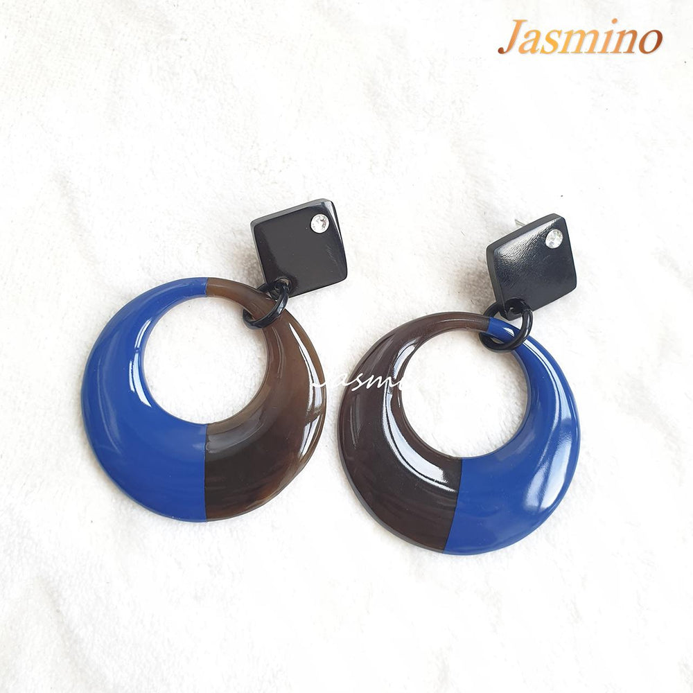 
                  
                    Handmade circular earrings feature a black and blue half with natural buffalo horn material in the natural light
                  
                
