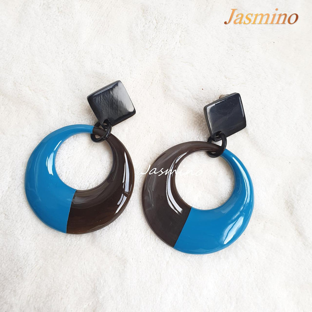 
                  
                    Handmade circular earrings feature a black and sky blue half with natural buffalo horn material in the natural light
                  
                