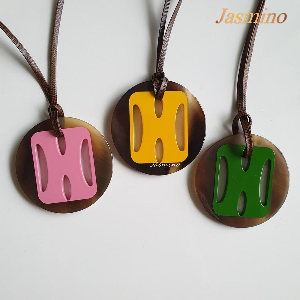 
                  
                    three round lacquer horn pendants on the light background, impressive gift for your friend
                  
                